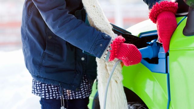 woman charging ev in winter gloves